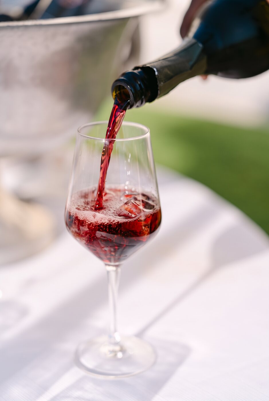 Pouring a ruby-red Singapore Spritz over ice